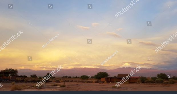 O por do sol ilumina-se na paisagem estéril e desolada do deserto de Atacama com os picos dos vulcões nevado da Cordilheira de Andes no fundo. Autor e Copyright Marco Ramerini